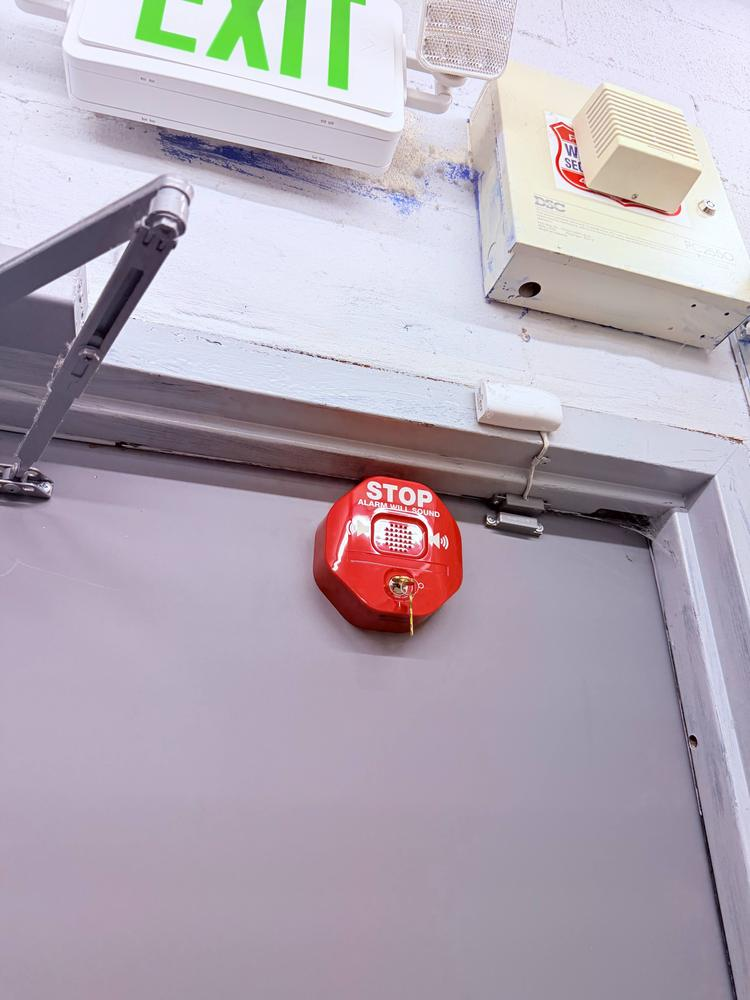 Commercial door closer and exit alarm device serviced on an emergency exit door