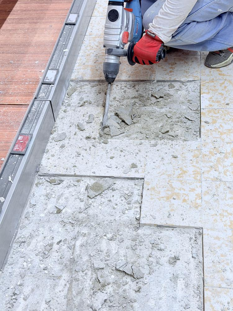 Hammer drill removing floor tile and thinset during commercial demolition