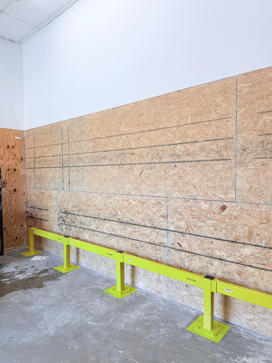 Steel guard rails installed along a warehouse wall to prevent repeat impact damage